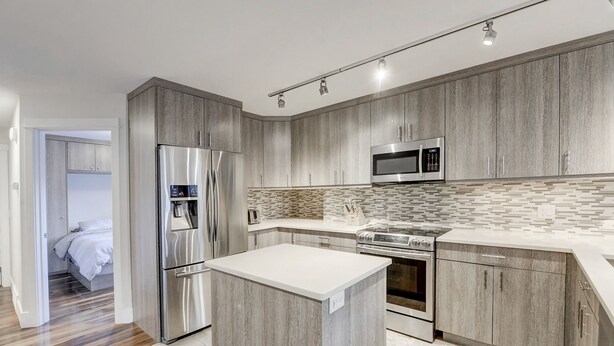 A modern kitchen with wooden cabinets, stainless steel appliances, and a tiled backsplash. - Beautiful Canmore Home with views and walk to DT (Canmore)