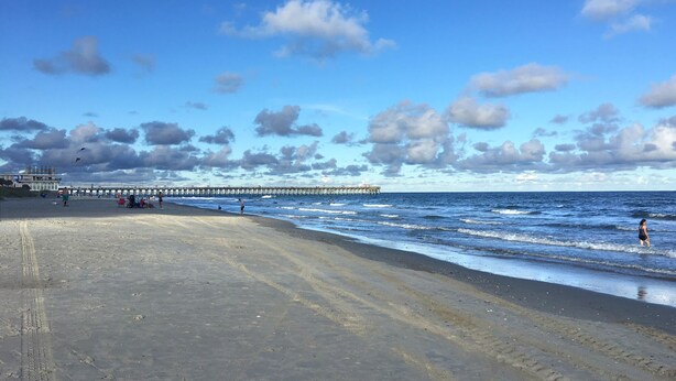 A beach with a pier extending into the ocean, sandy beach, and footprints in the sand. - Amazing Luxury Direct Ocean Front 1BD/1BA,  Modern Decor. Great Location! (Myrtle Beach)