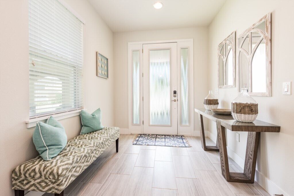 A hallway with a bench, a console table with baskets, and a door with frosted glass panels.
