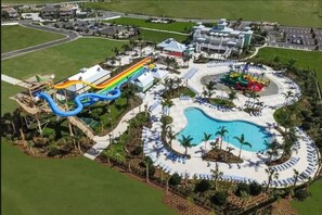 A resort with a large pool, a water park with slides, and a parking area.