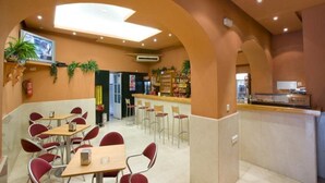 Un restaurante con área de bar, mesas y una pantalla de televisión.