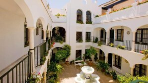 Un patio con edificios blancos, paseos en arco y plantas en macetas.