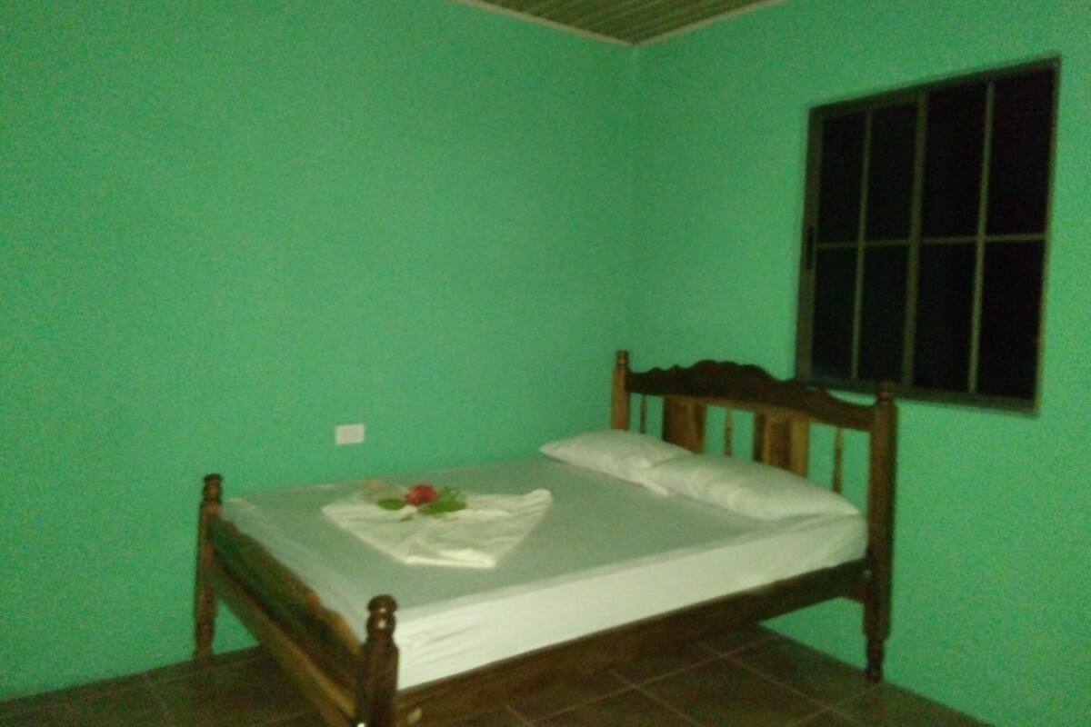 Een eenpersoonsbed in een kamer met groene wanden en een raam.