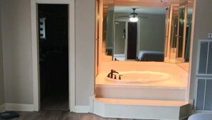 Une chambre dotée d’une banquette intégrée, d’un ventilateur de plafond et d’un grand miroir.