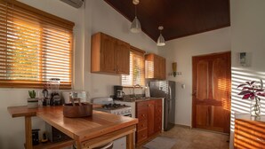 A kitchen with wooden cabinets, a stove, a refrigerator, and a sink. There are two pendant lights hanging from the ceiling. - Torio guesthouse with panoramic view- Kokomo (Torio)