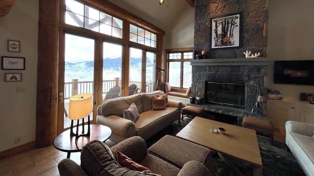 Una sala de estar acogedora con chimenea de piedra, ventanas amplias con vistas y asientos cómodos.