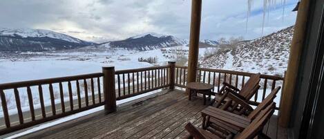 Eine Holzterrasse mit Blick auf eine verschneite Landschaft und Berge.