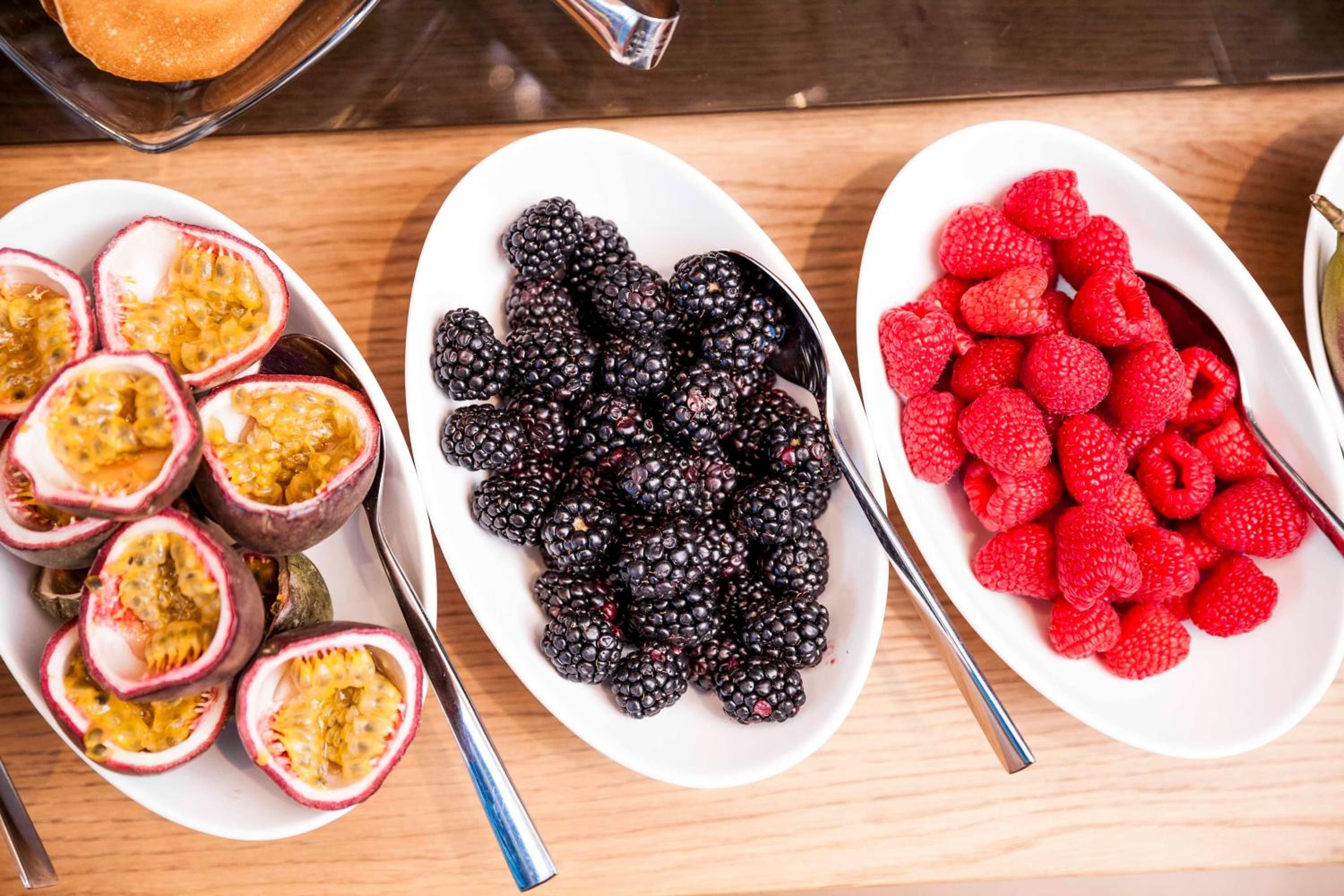 A table with three white plates of different fruits.