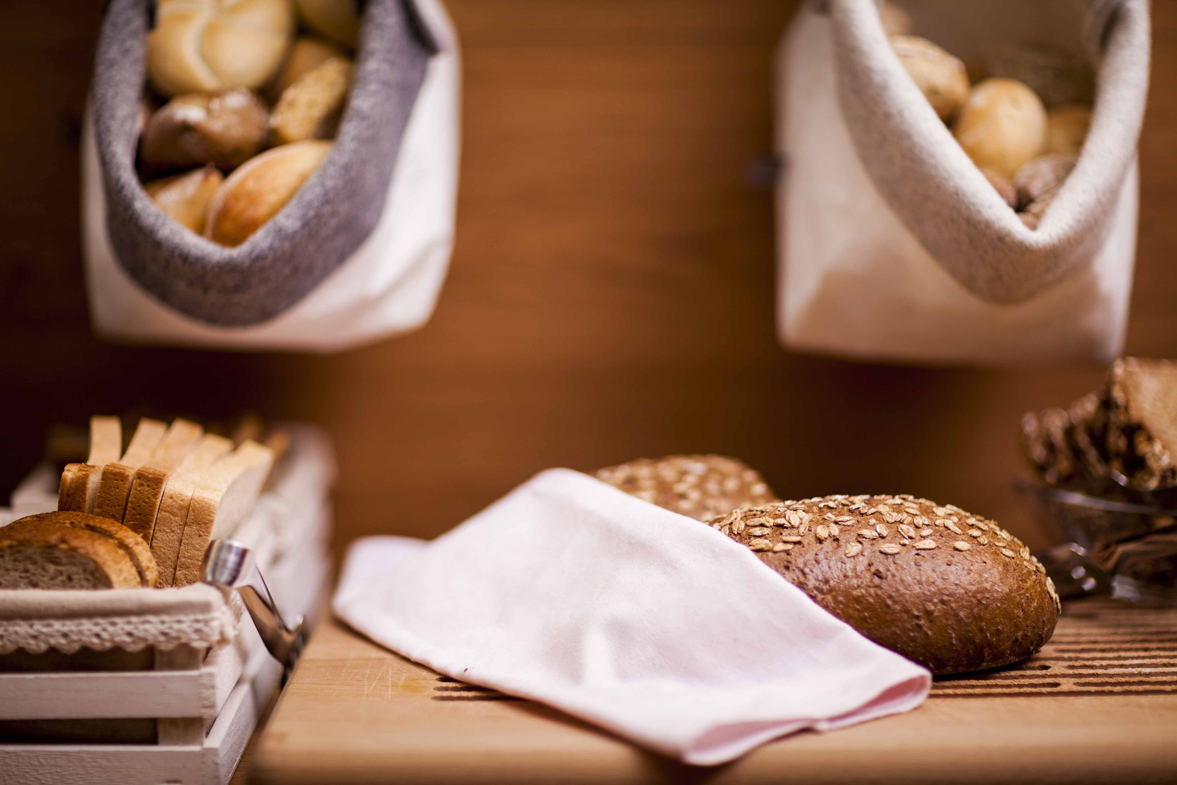 Ein Holztisch mit verschiedenen Brotsorten und einer Stoffserviette.