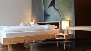 A minimalist bedroom with a wooden bed frame, white bedding, and a wall-mounted lamp.