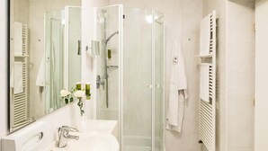 Un baño moderno con cabina de ducha de vidrio, un lavabo blanco y un espejo grande.