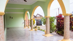 Un espacio al aire libre techado con suelo de baldosas, arcos y plantas en macetas.