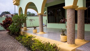 Un edificio con un patio empedrado, columnas amarillas y plantas en macetas.