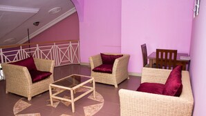 Una habitación con muebles de mimbre, una mesa de centro de vidrio y una pared morada.