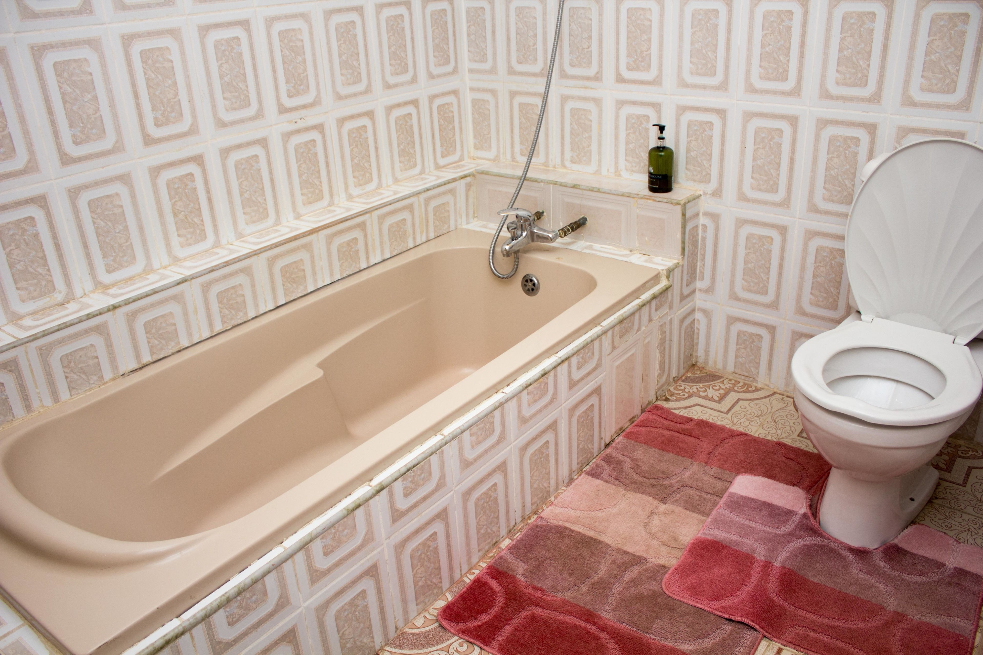 A bathroom with a bathtub, toilet, and a patterned wall.