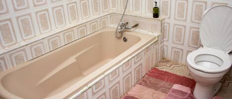 A bathroom with a bathtub, toilet, and a patterned wall.