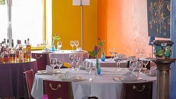 Un interior de restaurante con mesas listas para comer, una variedad de botellas a un lado y una lámpara decorativa.