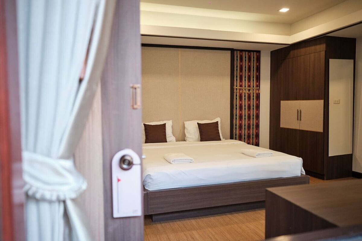 A hotel room with a large bed, a wardrobe, and a desk.