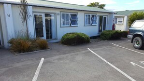 A single-story building with numbered windows, a parking lot, and a parked vehicle. - The Ohakune Central Backpackers & Cabins (Ohakune)