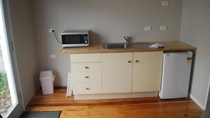 A compact kitchenette with a microwave, sink, and refrigerator. - The Ohakune Central Backpackers & Cabins (Ohakune)