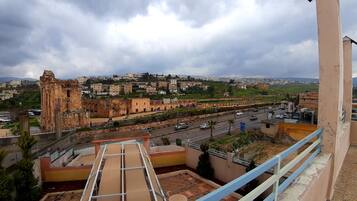 Una terraza en la azotea con vistas a un casco histórico, que incluye ruinas antiguas y edificios modernos.