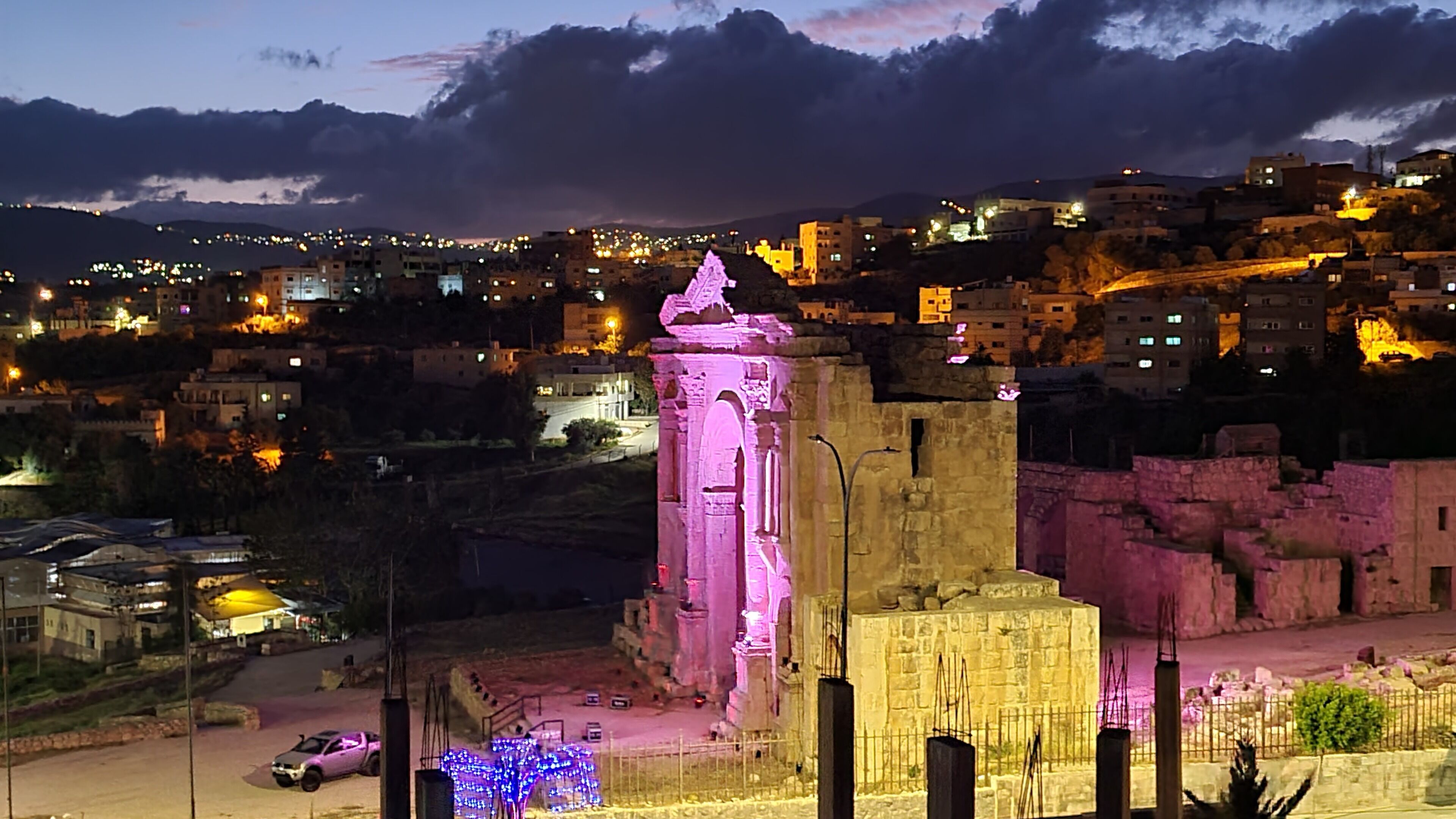 Um edifício histórico com uma torre imponente, cercado por uma paisagem urbana ao entardecer.