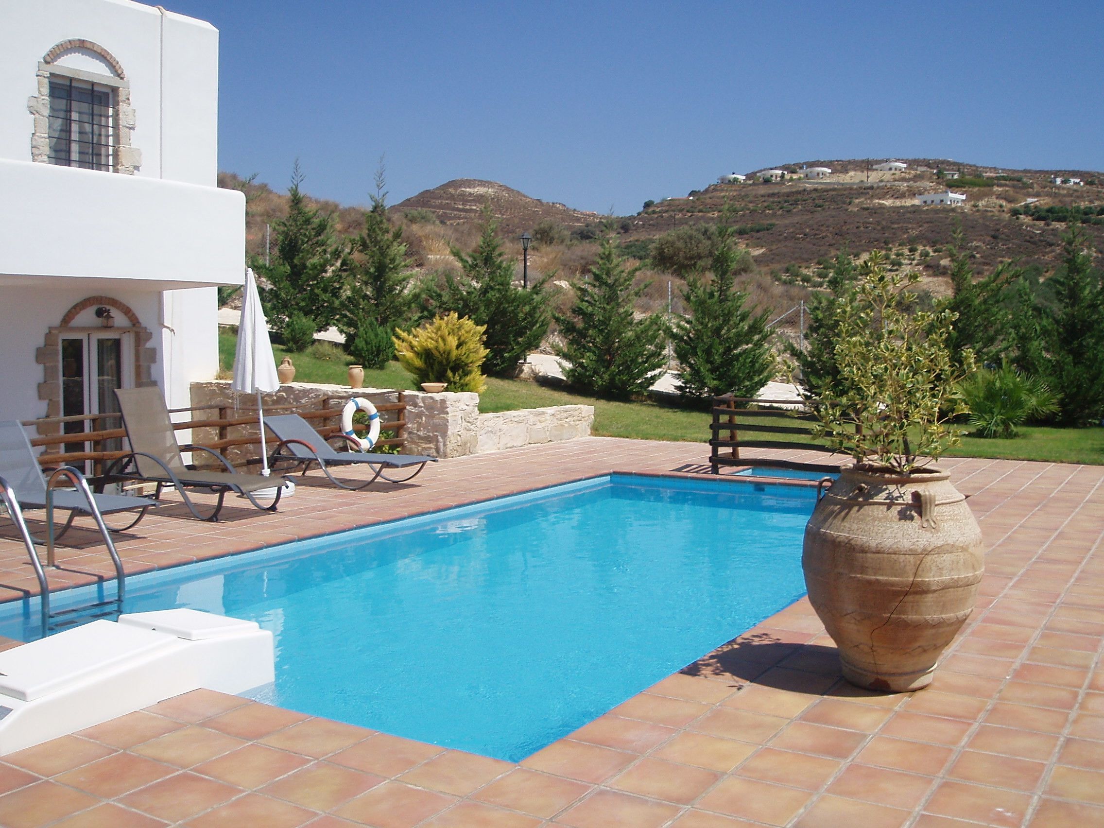 A swimming pool with lounge chairs and a large vase.