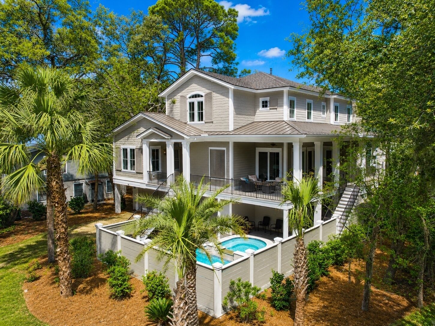 A two-story house with a covered patio, a swimming pool, and a landscaped garden.