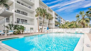 A swimming pool with a white pool deck, surrounded by lounge chairs and palm trees. - Award Winning Direct Gulf Front Condo with a Fantastic Sunset View (Indian Shores)