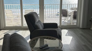 A spacious living room with a large window overlooking the beach and ocean. - Award Winning Direct Gulf Front Condo with a Fantastic Sunset View (Indian Shores)