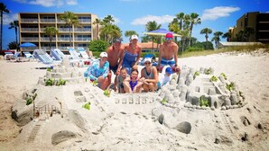 A beach scene with a group of people sitting in a sandcastle.