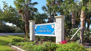 A welcome sign for Longboat Key, surrounded by palm trees and flowering plants.