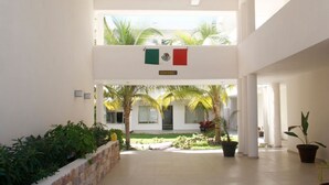 A spacious indoor area with a high ceiling, a central open space with a view of a building outside, and a flag hanging from the ceiling.