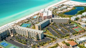 Vista aérea de un hotel costero con varias construcciones, una playa y un estacionamiento.