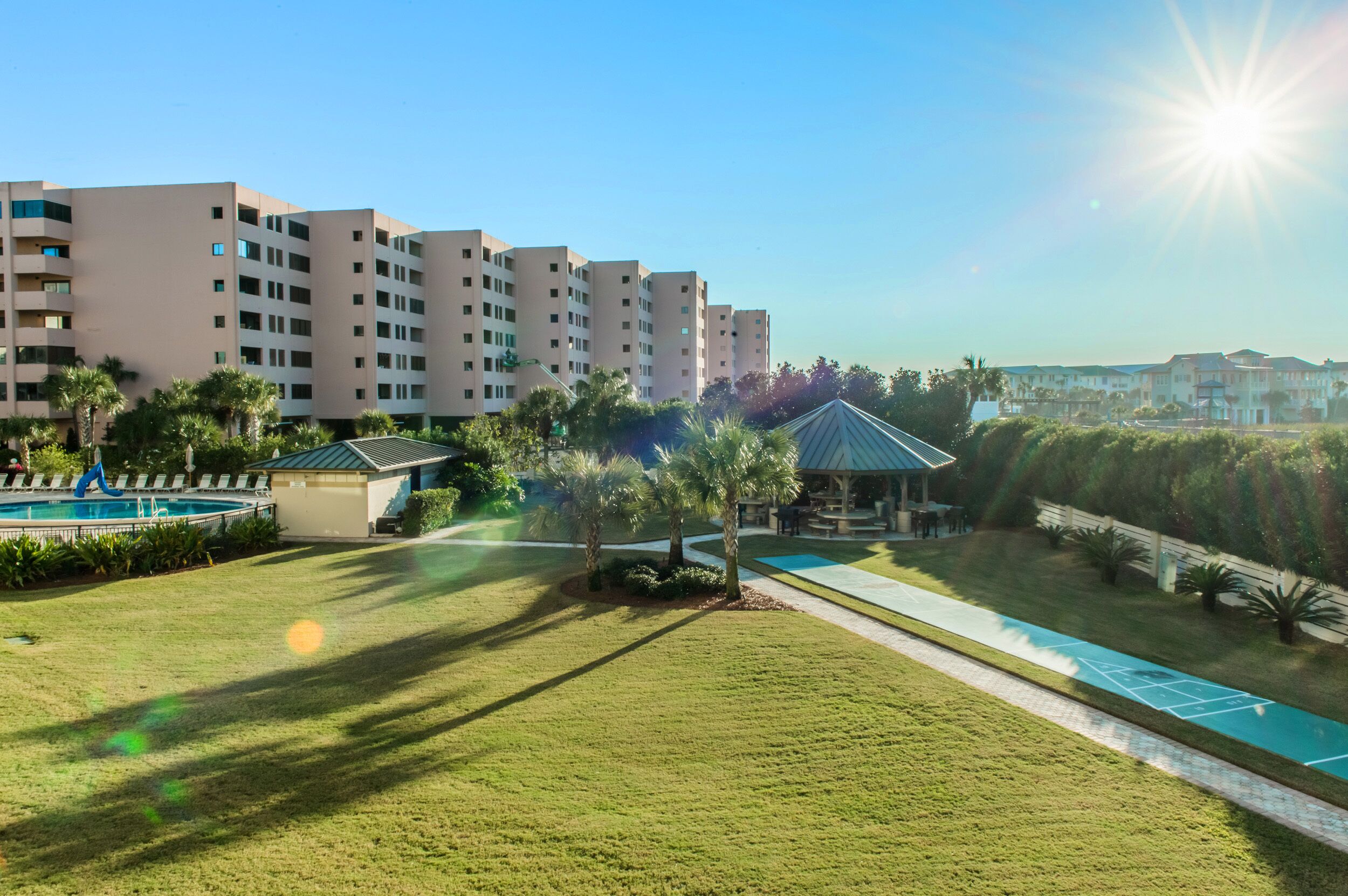 A residential building complex with a swimming pool, a gazebo, and a tennis court.