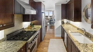 A modern kitchen with dark wood cabinets, granite countertops, stainless steel appliances, and a view to the living area. - Gulf View Two Story Condo in Watersound | 110B (Panama City Beach)