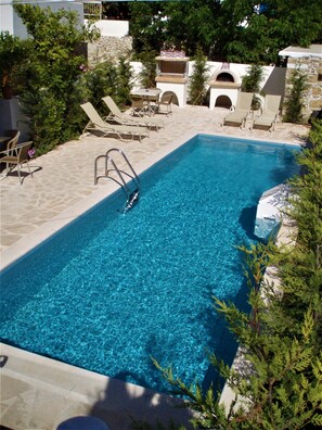 Una piscina al aire libre, sombrillas, sillones reclinables de piscina