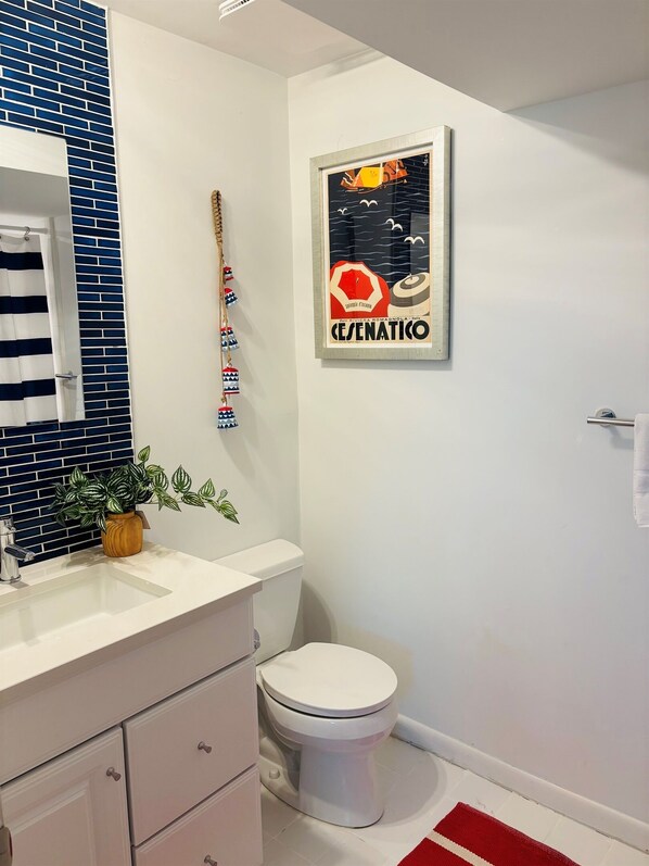 A modern bathroom with a white sink, a toilet, and a shower curtain. - Oceanfront, Private Beach Access (Hilton Head)