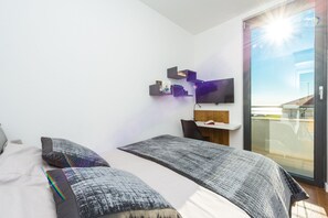 Een moderne slaapkamer met twee bedden, een televisie en een balkon.