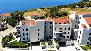 Un complejo moderno de apartamentos con varios edificios, un estacionamiento y vista al mar.