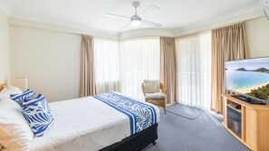 Una habitación de hotel con cama, sillón, televisión y vista al mar.