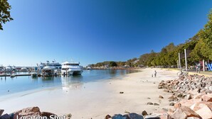 A marina with boats docked, a sandy beach with rocks, and a playground. - Seashells, 2,21-23 Magnus Street -Unit with Air con, complex lift and pool, close to town (Nelson Bay)