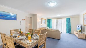 Una habitación de hotel moderna con zona de comedor, sofá y televisor.