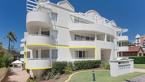 A multi-story white building with balconies, a gated entrance, and a well-maintained lawn. - Seashells, 2,21-23 Magnus Street -Unit with Air con, complex lift and pool, close to town (Nelson Bay)