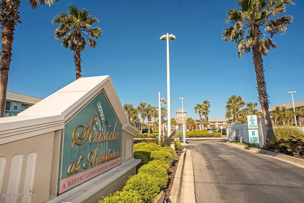 A sign for Seaside at Atlantis, a resort condominium community, with a clear sky and palm trees.