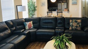 Ein Wohnzimmer mit einem schwarzen Ledersofa, einem Couchtisch und einem Deckenventilator.