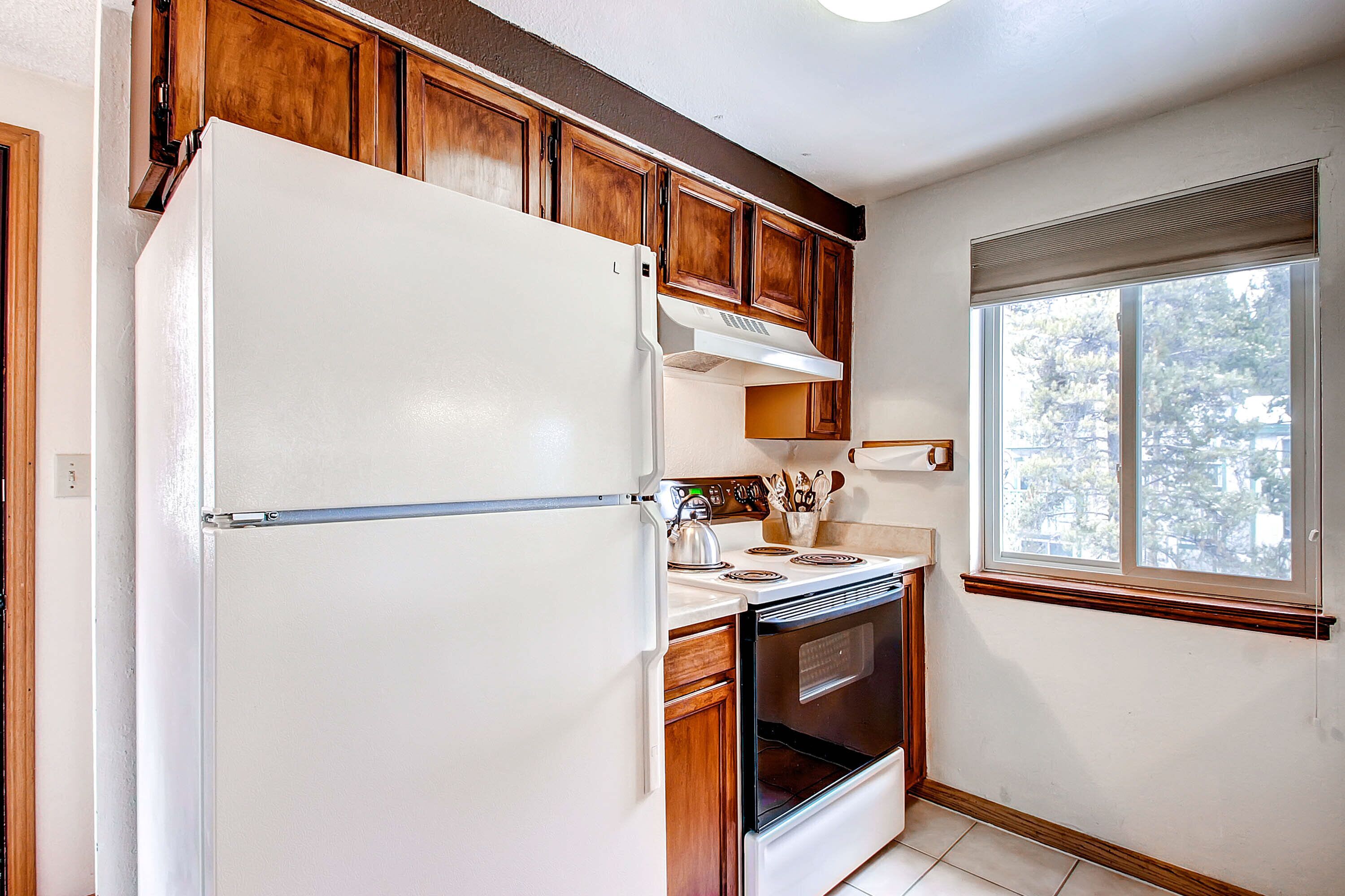 A kitchen with wooden cabinets, a white refrigerator, a stove, and an oven.