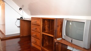 Une pièce comprenant un meuble en bois, un téléviseur et un bureau.