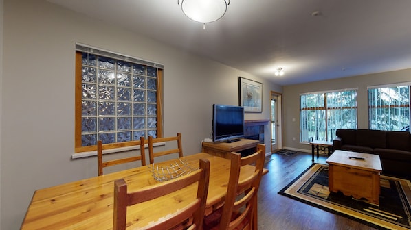 A living room with a wooden dining table, chairs, a television, and a couch.