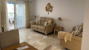 A living room with a beige sofa, a coffee table with papers, a lamp, and a decorative wall piece. - Location, location, location! Front line beach with all Nerja amenities to hand. (Nerja)